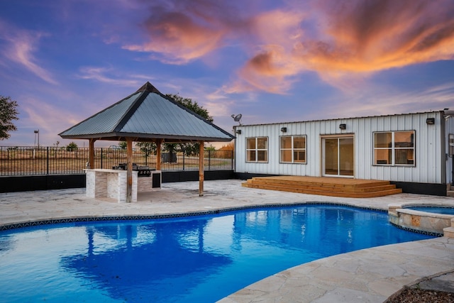 pool at dusk featuring an in ground hot tub, a patio area, and a gazebo