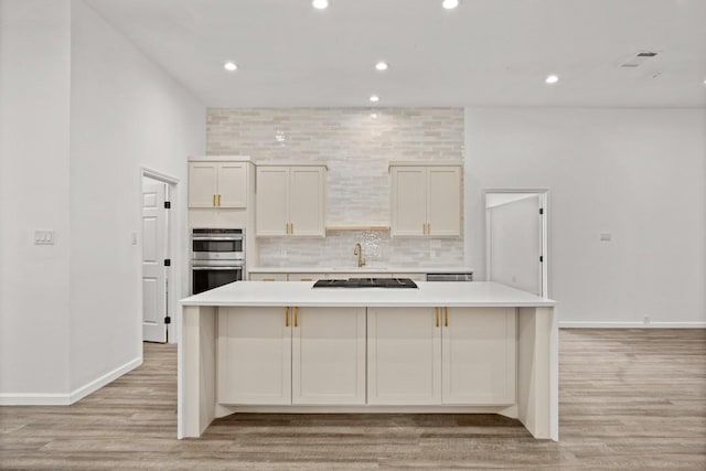 14409 Bois D Arc Ln, Manor, TX 78653 - kitchen with stainless steel double oven, decorative backsplash, light wood-style floors, and light countertops