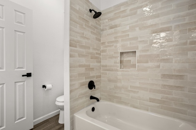 bathroom featuring toilet and tiled shower / bath