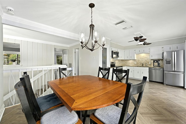 dining space featuring light parquet floors, ceiling fan with notable chandelier, crown molding, and sink