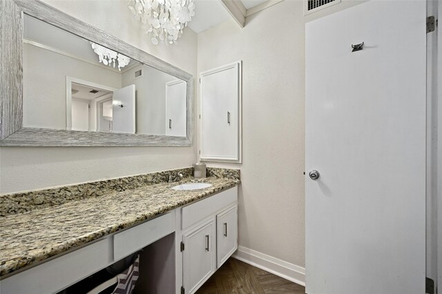 bathroom with vanity, an inviting chandelier, and parquet flooring