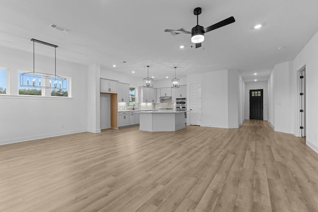 unfurnished living room with ceiling fan and light hardwood / wood-style flooring