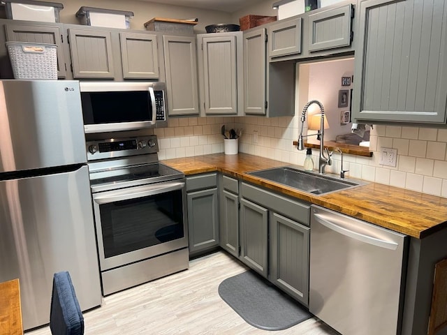 kitchen with sink, appliances with stainless steel finishes, gray cabinets, and backsplash