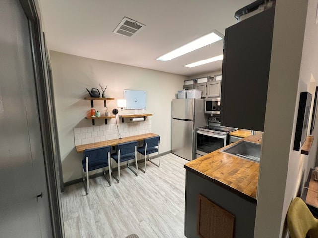 kitchen with gray cabinets, sink, appliances with stainless steel finishes, and light wood-type flooring