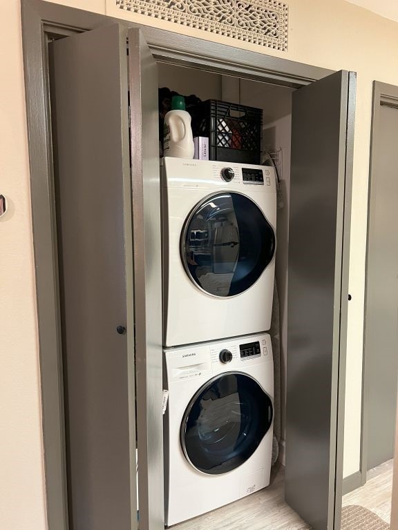 clothes washing area featuring light hardwood / wood-style floors and stacked washing maching and dryer