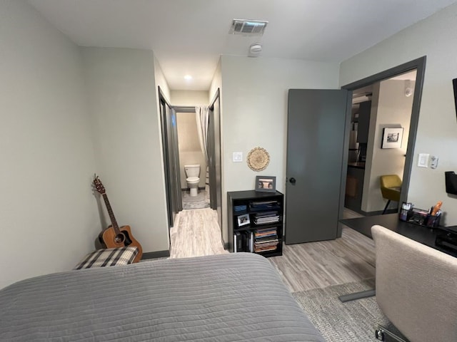 bedroom featuring light hardwood / wood-style flooring and connected bathroom