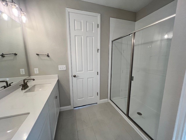 bathroom featuring an enclosed shower, tile patterned flooring, and dual bowl vanity