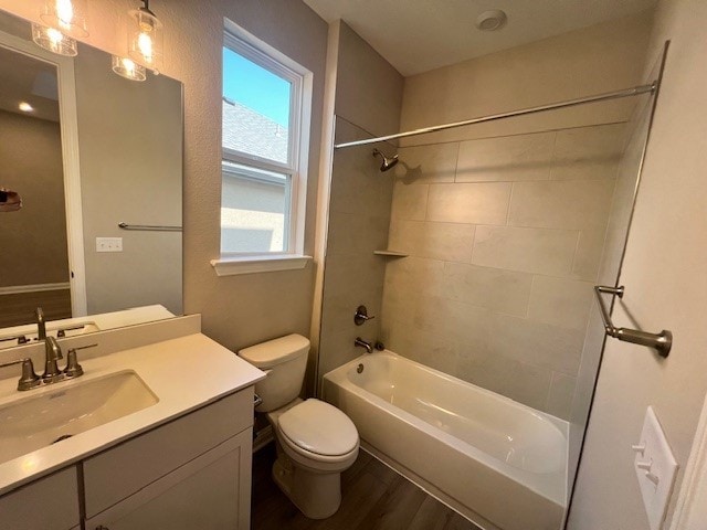 full bathroom featuring vanity, toilet, tiled shower / bath, and hardwood / wood-style floors