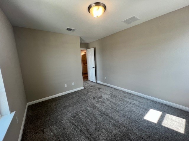 spare room featuring dark carpet