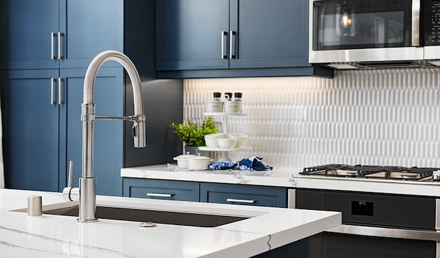 kitchen featuring light stone counters, blue cabinets, and stainless steel appliances