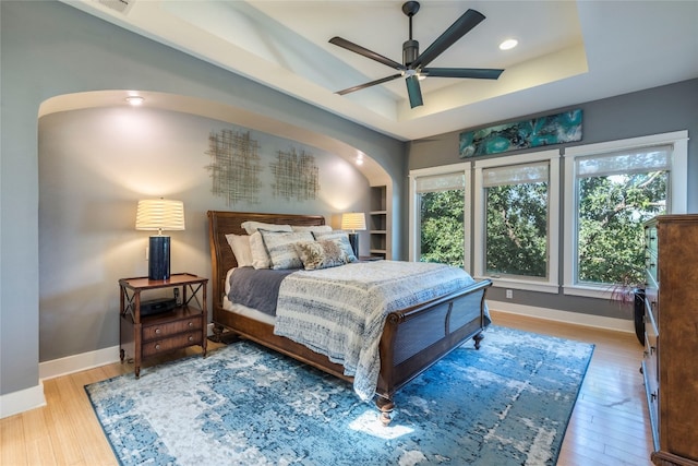 bedroom featuring a tray ceiling, light hardwood / wood-style flooring, and ceiling fan