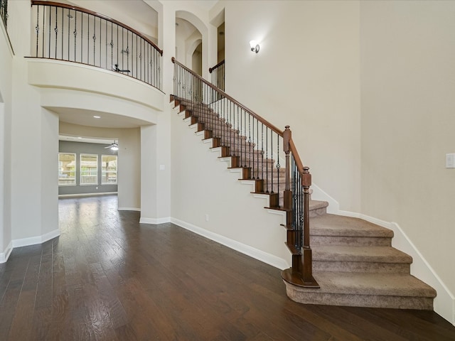 staircase with a towering ceiling and hardwood / wood-style floors