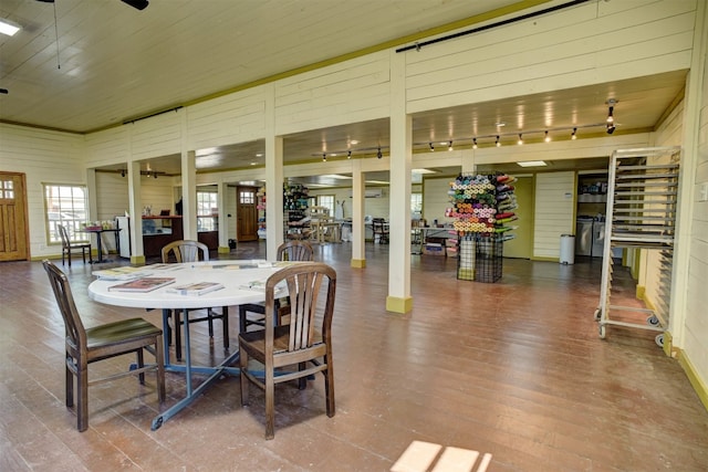 dining area featuring wooden walls, hardwood / wood-style floors, wood ceiling, and rail lighting