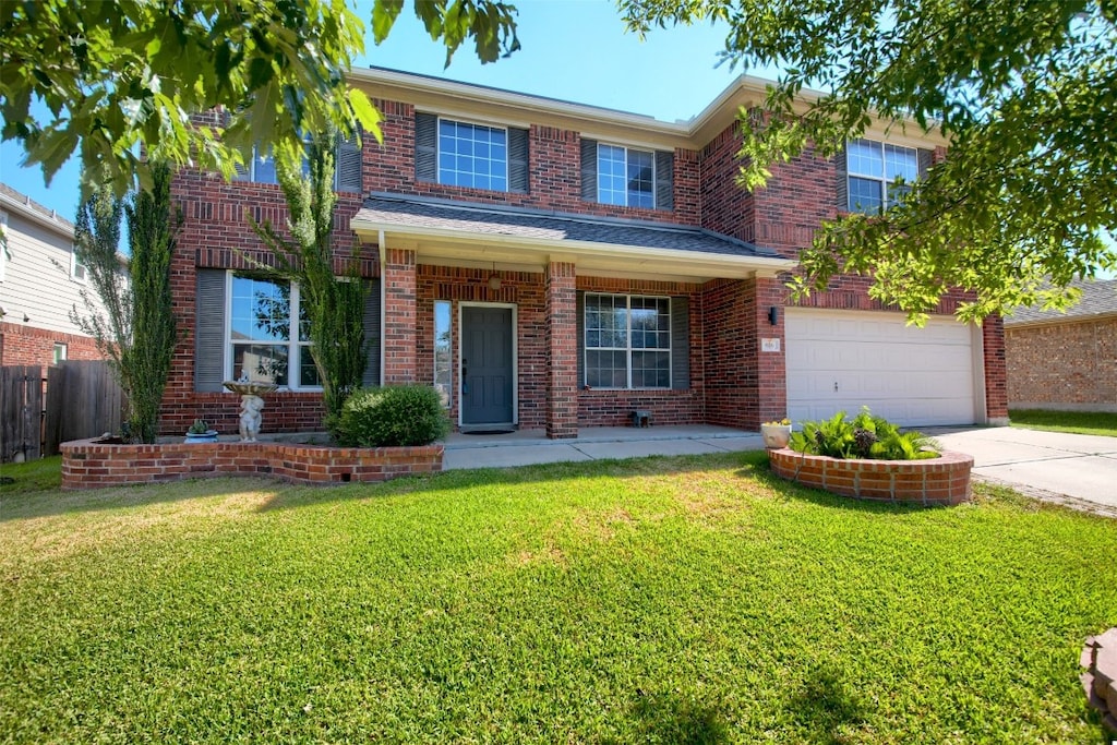 traditional-style house with a garage, brick siding, fence, concrete driveway, and a front yard