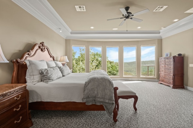 carpeted bedroom featuring ceiling fan, multiple windows, ornamental molding, and a tray ceiling