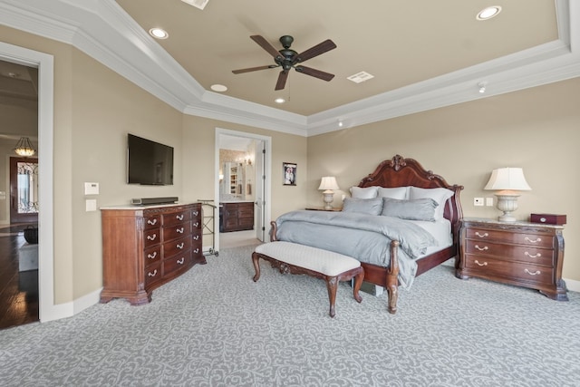 carpeted bedroom with ensuite bath, a tray ceiling, ceiling fan, and ornamental molding