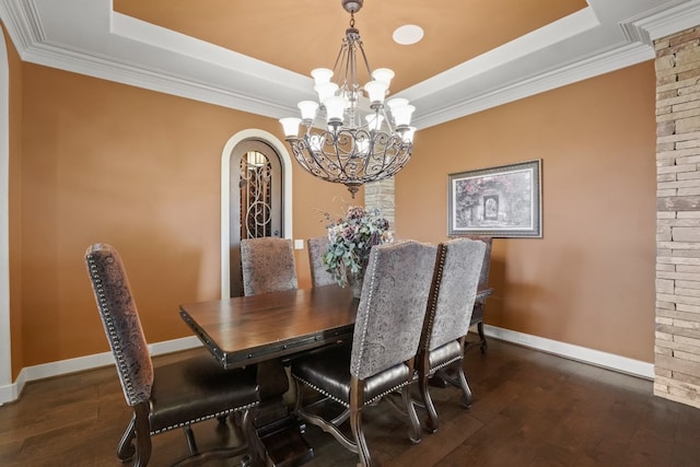 dining area with dark hardwood / wood-style flooring, an inviting chandelier, and a raised ceiling