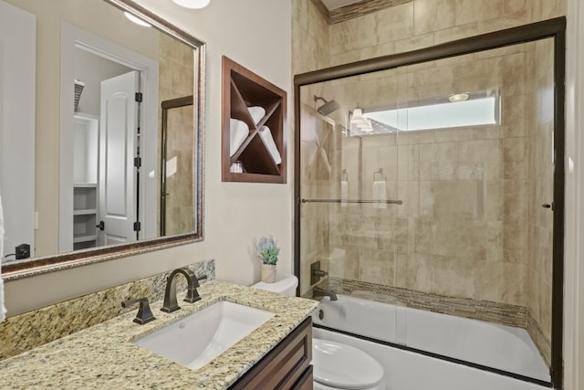 full bathroom featuring toilet, shower / bath combination with glass door, and vanity