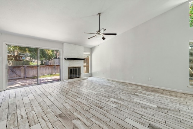 unfurnished living room with ceiling fan, light wood-type flooring, and a large fireplace