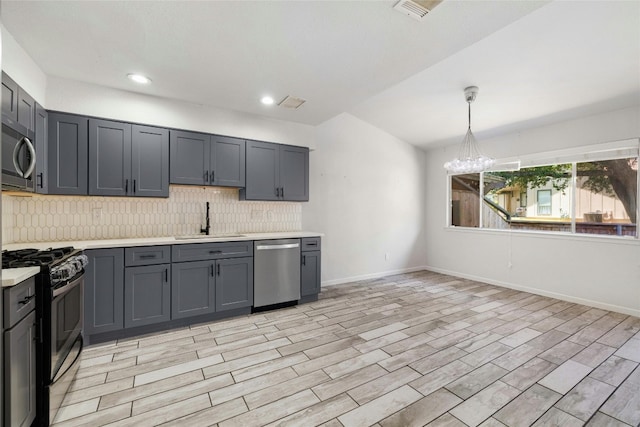 kitchen featuring a chandelier, light hardwood / wood-style floors, sink, gray cabinetry, and stainless steel appliances