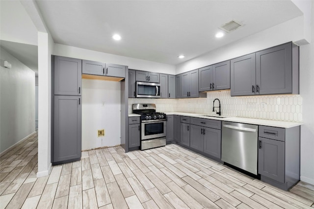 kitchen with gray cabinets, stainless steel appliances, and light hardwood / wood-style floors