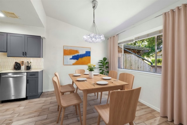 dining space featuring lofted ceiling, light wood-type flooring, and a chandelier