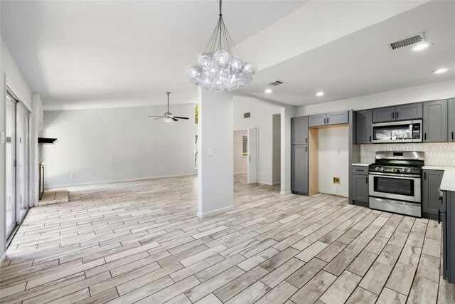 kitchen with appliances with stainless steel finishes, tasteful backsplash, ceiling fan with notable chandelier, gray cabinets, and light hardwood / wood-style flooring