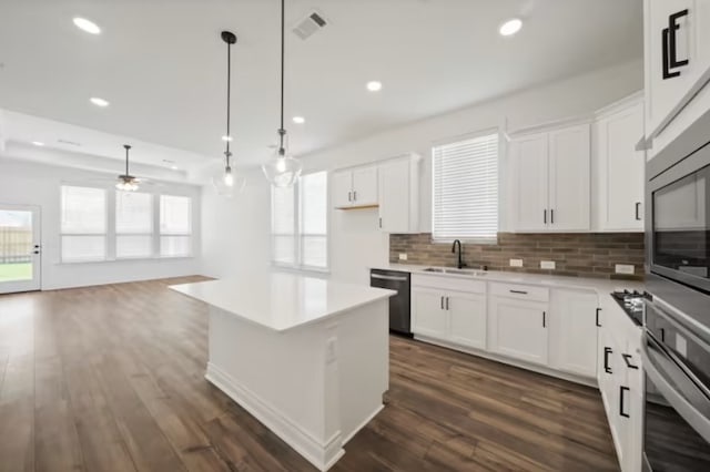 kitchen with tasteful backsplash, stainless steel appliances, white cabinets, sink, and dark wood-type flooring