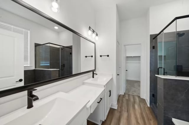 bathroom featuring a shower with shower door, double vanity, and hardwood / wood-style floors