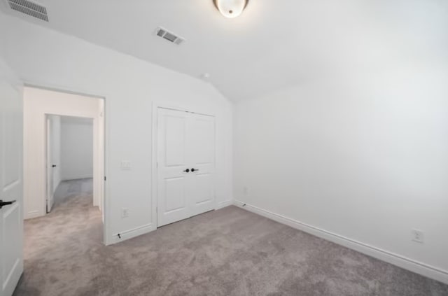 unfurnished bedroom featuring carpet flooring and vaulted ceiling