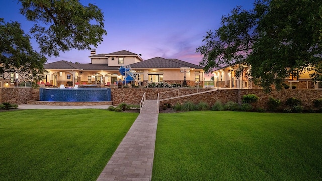 back house at dusk featuring a yard