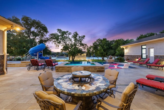 pool at dusk featuring a patio area