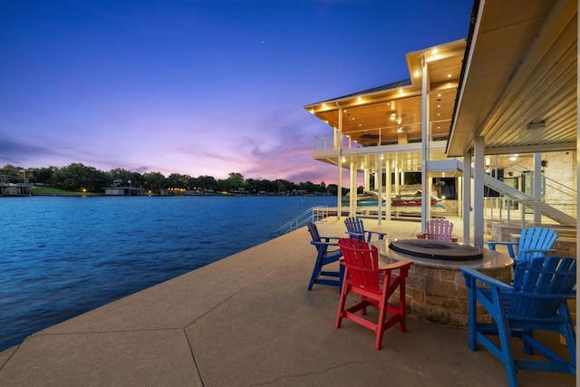 patio terrace at dusk with a water view and a fire pit