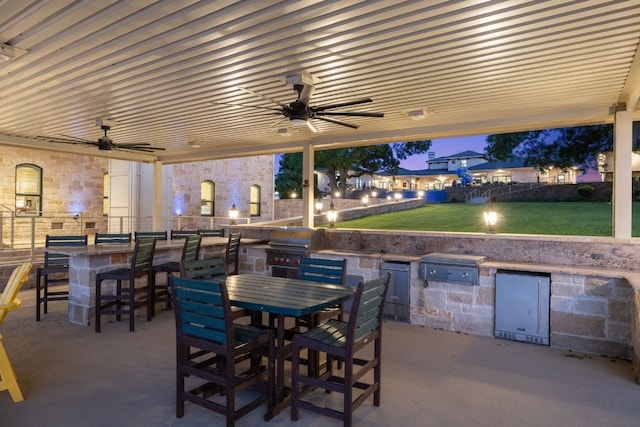 view of patio featuring exterior kitchen, ceiling fan, and a bar