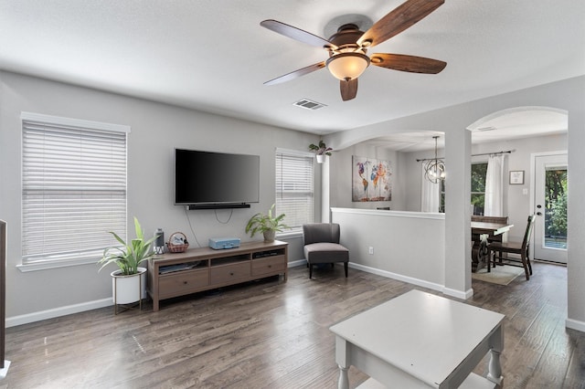 living room featuring dark wood-type flooring and ceiling fan with notable chandelier