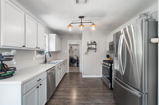 kitchen featuring washer / dryer, sink, white cabinets, stainless steel appliances, and dark wood-type flooring