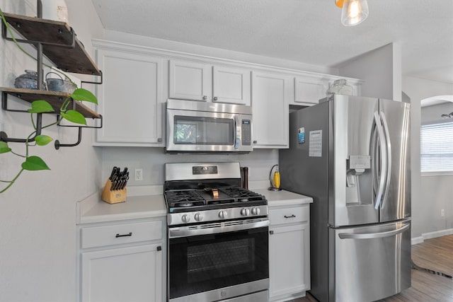 kitchen with white cabinetry, hardwood / wood-style floors, a textured ceiling, and appliances with stainless steel finishes