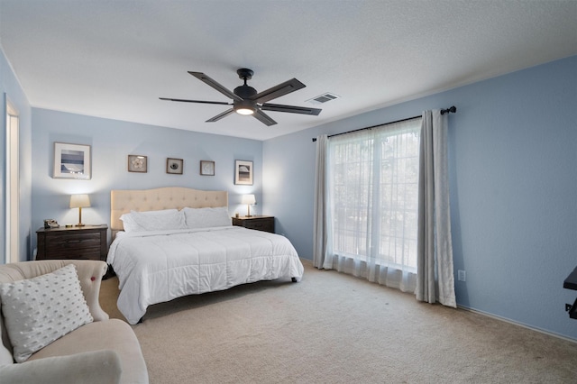 carpeted bedroom featuring ceiling fan and a textured ceiling