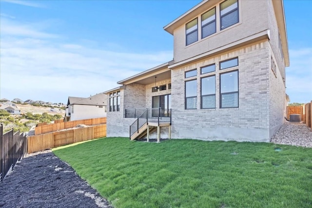 rear view of house featuring central AC and a lawn