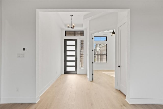 foyer entrance with ceiling fan with notable chandelier and light hardwood / wood-style flooring