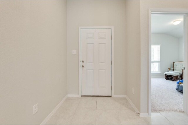 hallway with light tile patterned flooring and lofted ceiling