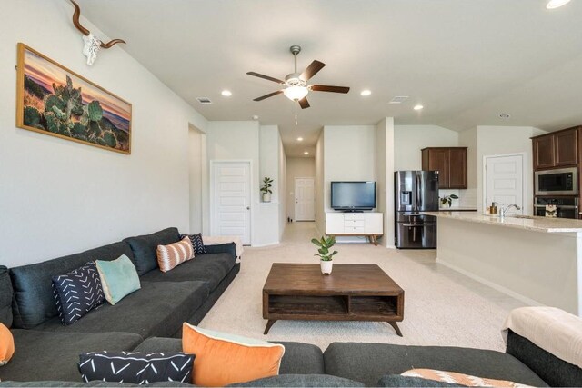 living room featuring sink, light carpet, and ceiling fan