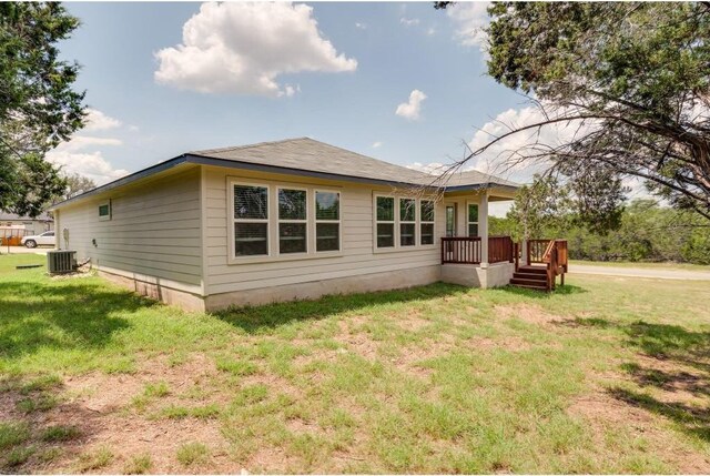 exterior space featuring central air condition unit, a deck, and a yard