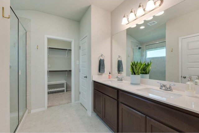 bathroom with tile patterned flooring, double sink vanity, and a shower with shower door