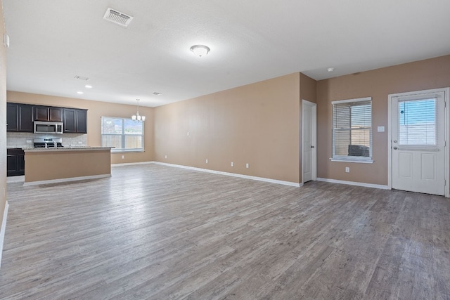 unfurnished living room with a notable chandelier and light hardwood / wood-style floors