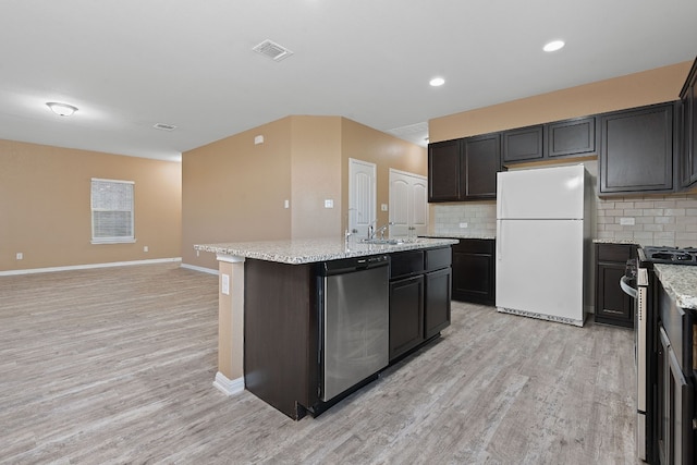 kitchen featuring decorative backsplash, appliances with stainless steel finishes, light wood-type flooring, and an island with sink