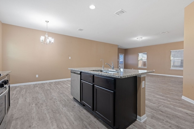 kitchen with light hardwood / wood-style flooring, a kitchen island with sink, stainless steel dishwasher, decorative light fixtures, and sink