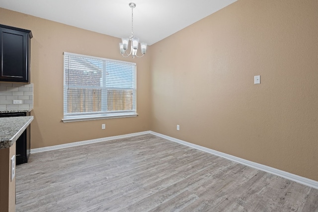 unfurnished dining area featuring light hardwood / wood-style flooring and an inviting chandelier