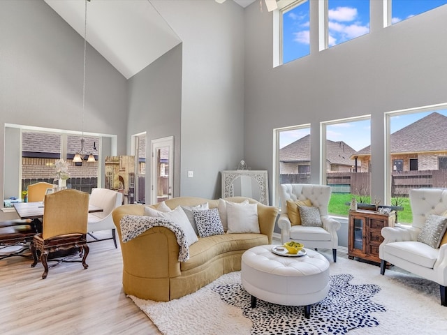 living room with a fireplace, light wood-type flooring, and a high ceiling