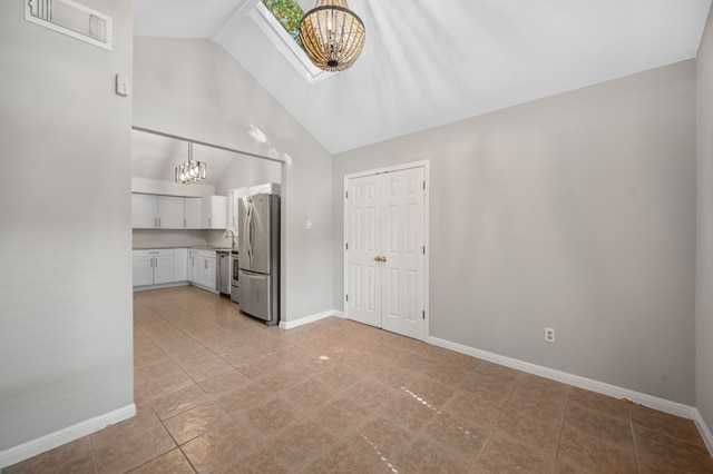 kitchen featuring white cabinetry, stainless steel fridge, a notable chandelier, and light tile patterned floors